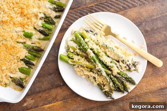 Velvety Baked Asparagus Alfredo 3 Creamy Baked Asparagus Alfredo on white plate with gold fork next to baking dish of creamy baked asparagus Alfredo