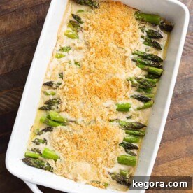 Creamy Baked Asparagus Alfredo in white baking dish on wooden surface