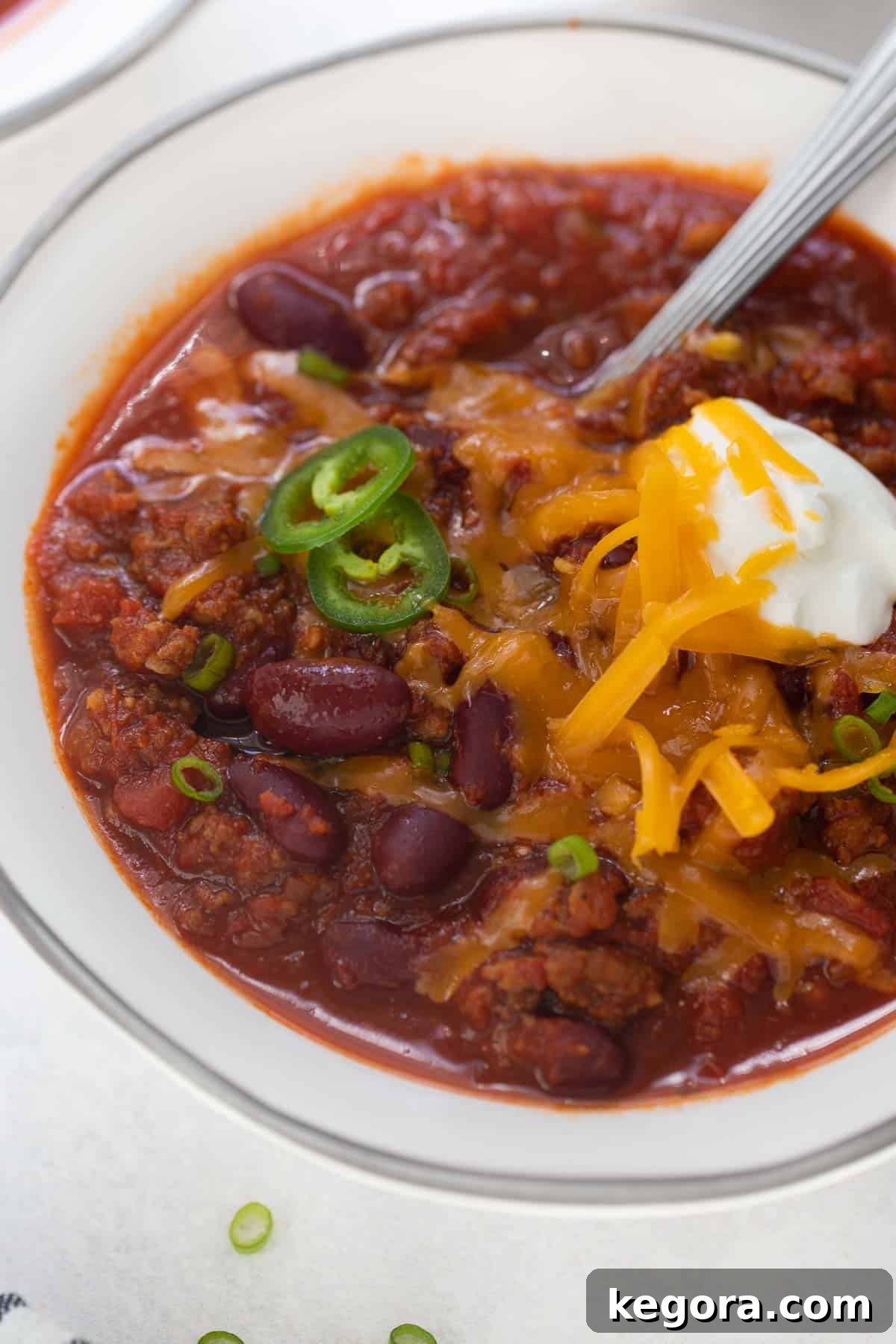 Hearty Gluten-Free Chili 5 A close-up shot of rich, steaming gluten-free chili served in a white bowl, generously garnished with a dollop of sour cream and a sprinkle of shredded cheese, highlighting its comforting texture and vibrant colors.