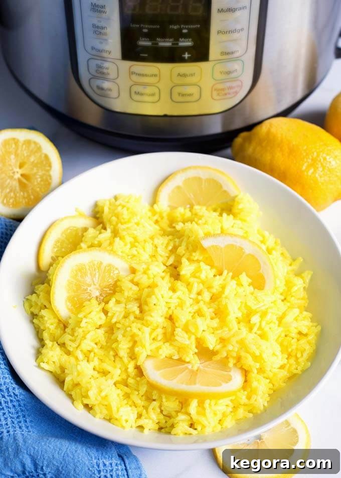 Lemon Rice in a white bowl with sliced lemons in front of pressure cooker