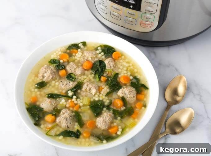 Effortless Instant Pot Italian Wedding Soup 4 A bowl of Instant Pot Italian Wedding Soup with two spoons in front of the pressure cooker, showcasing a perfectly prepared meal.