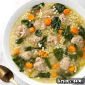 Instant Pot Italian Wedding Soup in a white bowl next to two spoons, ready to be enjoyed.