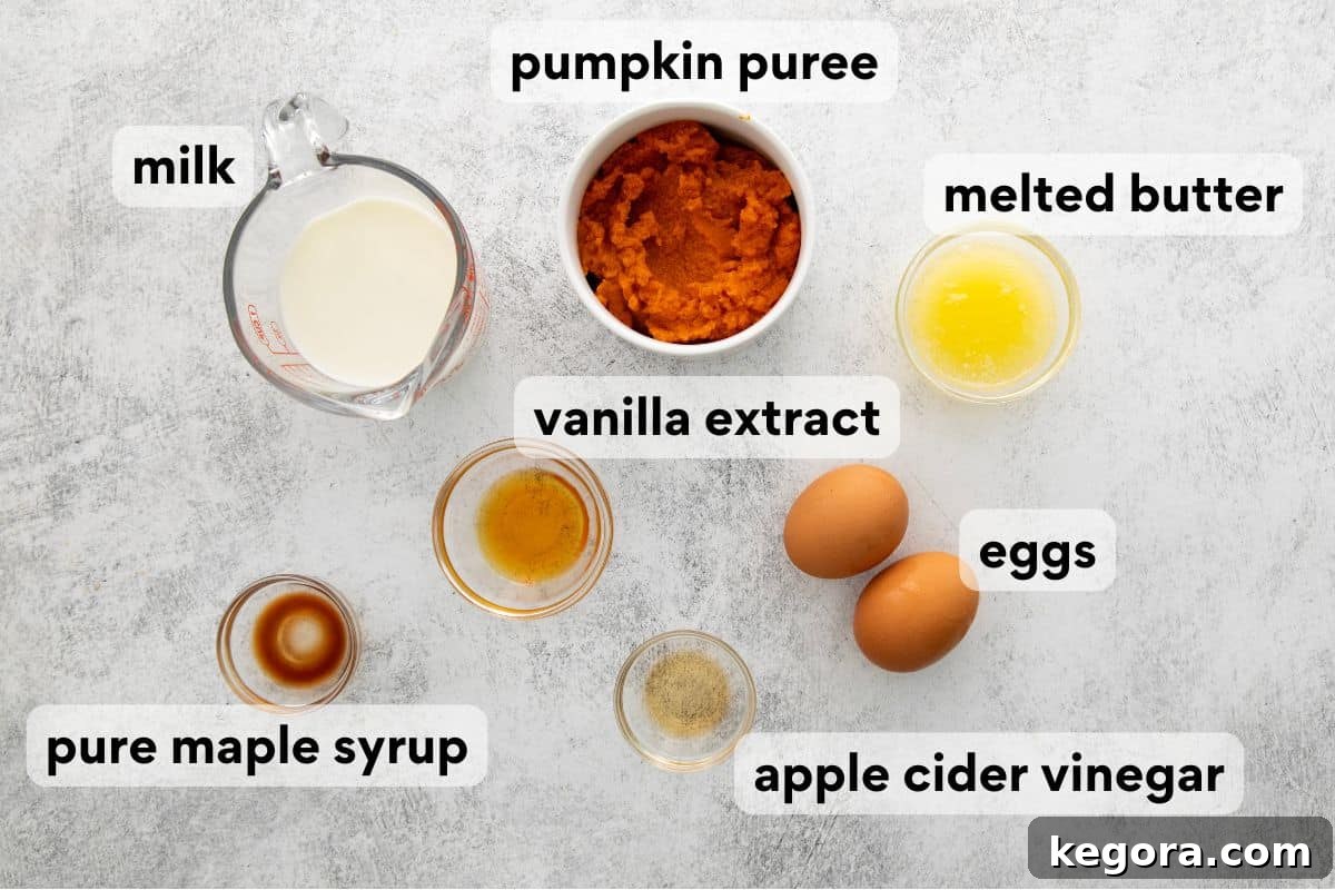 Spiced Oat Flour Pumpkin Pancakes 5 Carefully measured wet ingredients for pumpkin pancakes, including pumpkin puree, milk, eggs, melted butter, vanilla extract, apple cider vinegar, and maple syrup, neatly arranged on a kitchen counter.