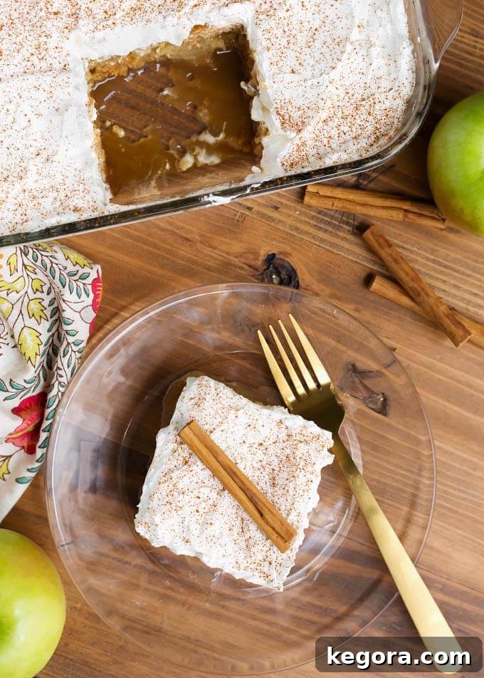Spiced Caramel Apple Poke Cake 8 Overhead view of a beautiful slice of Caramel Apple Poke Cake on a clear glass plate with a gold fork, resting in front of the remaining cake in a baking dish.