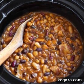 Baked Beans in a slow cooker with wooden mixing spoon