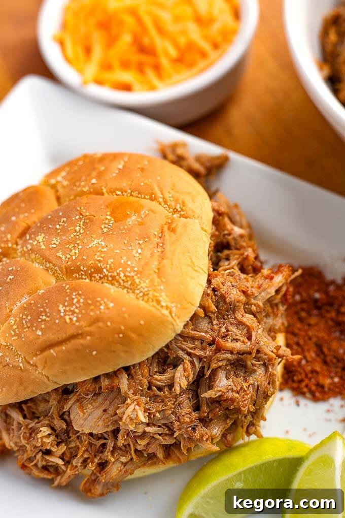 Close up of Instant Pot Pulled Pork on a hamburger bun on a white serving platter