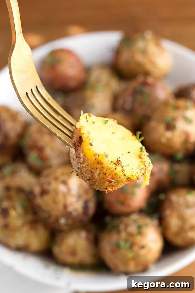 Close-up of a fork holding a perfectly crispy Air Fryer Garlic Parmesan Potato, showing its golden exterior.