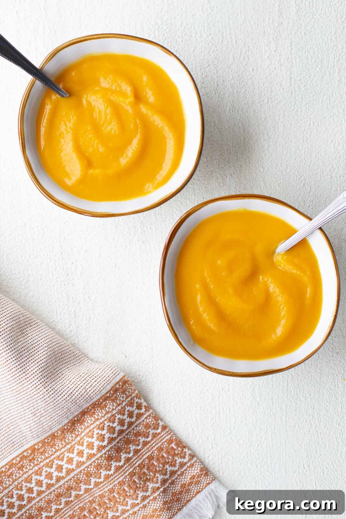two bowls of butternut squash leek soup garnished with fresh herbs