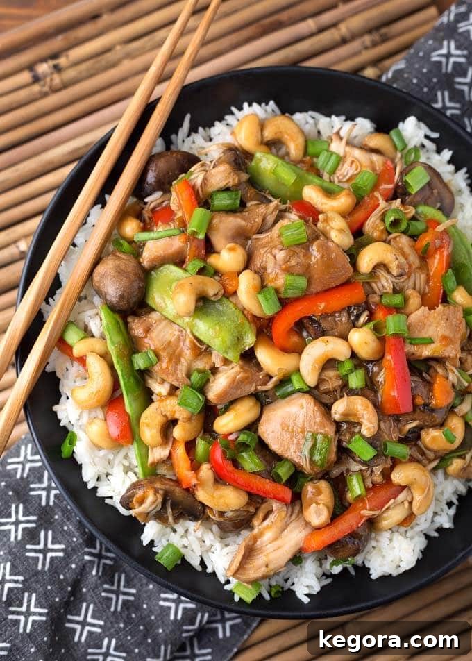 Quick and Delicious Instant Pot Cashew Chicken 2 Cashew Chicken over rice on black plate with wooden chopsticks, ready to serve