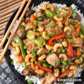 Cashew Chicken over rice on black plate with wooden chopsticks