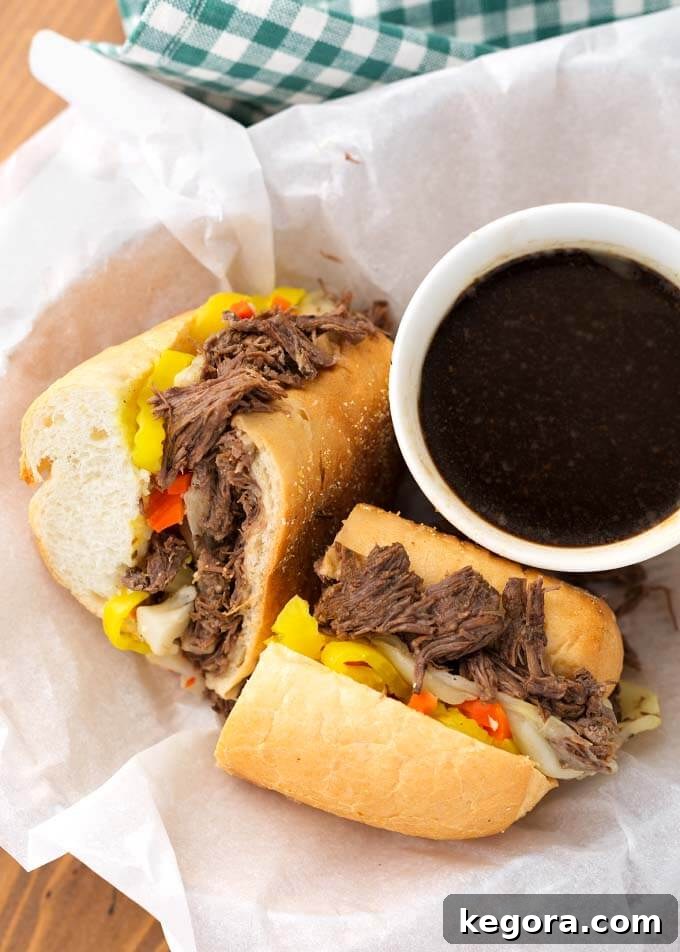 Ultimate Instant Pot Italian Beef 3 Italian Beef sandwich cut in half next to small bowl of sauce in white paper-lined basket