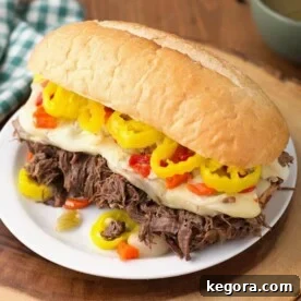 Ultimate Instant Pot Italian Beef 6 Italian Beef hoagie on white plate on wooden board