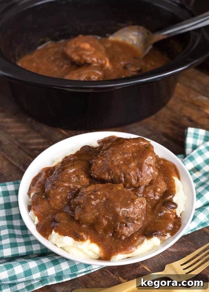 Salisbury Steak on white plate in front of a slow cooker