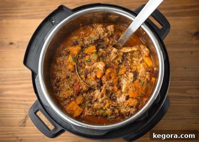 Sweet Potato Quinoa Chicken Chili in pressure cooker with a ladle, showing its hearty consistency.