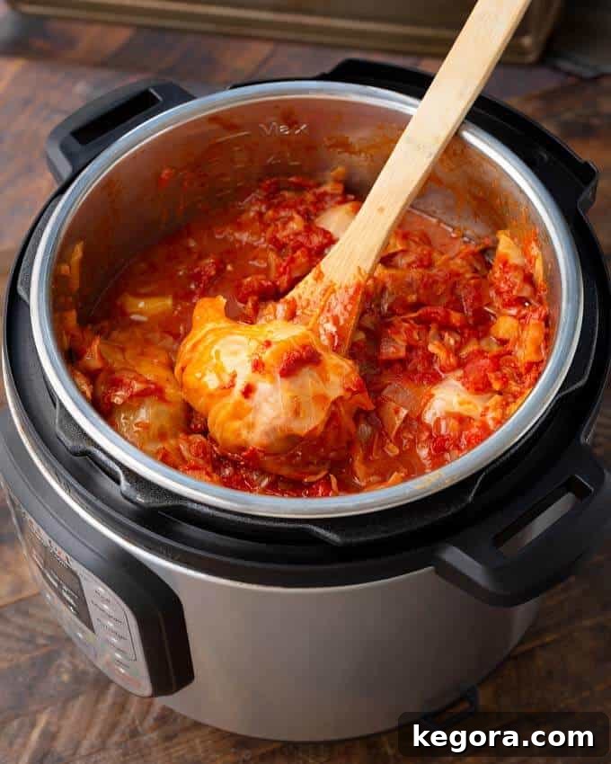Comforting Instant Pot Cabbage Bundles 9 A vibrant close-up of Pressure Cooker Stuffed Cabbage Rolls, rich in tomato sauce, nestled directly in the Instant Pot after cooking.