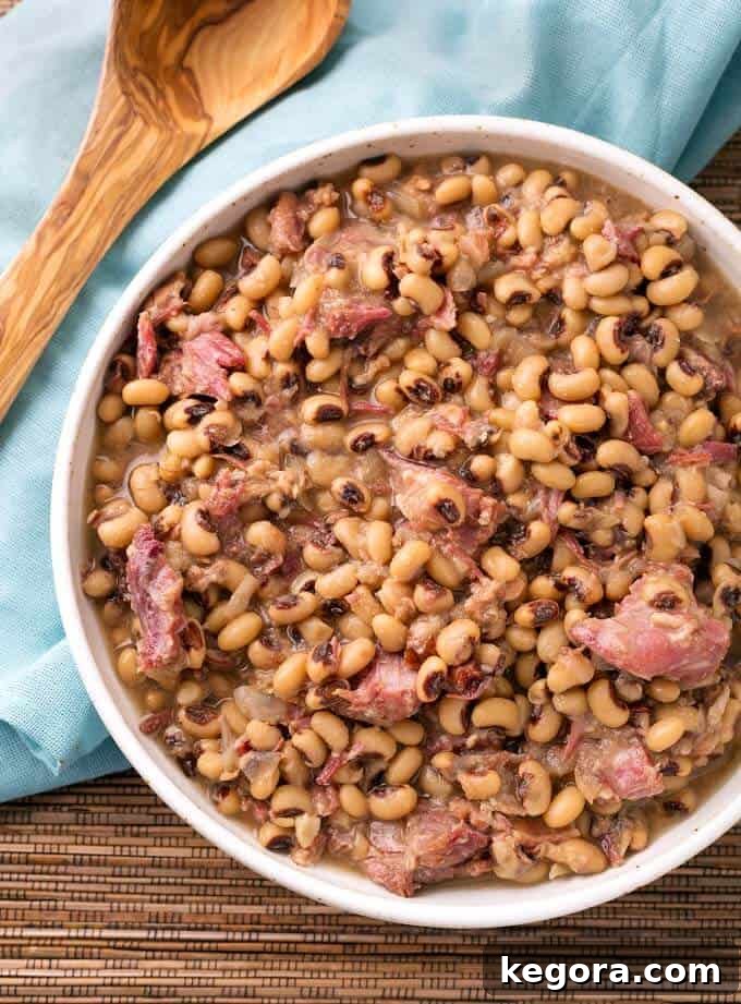 A beautifully presented bowl of Southern Instant Pot Black Eyed Peas, garnished and ready to serve, with a rustic wooden spoon nearby.