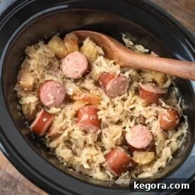 Slow Cooker Sauerkraut and Kielbasa with wooden mixing spoon