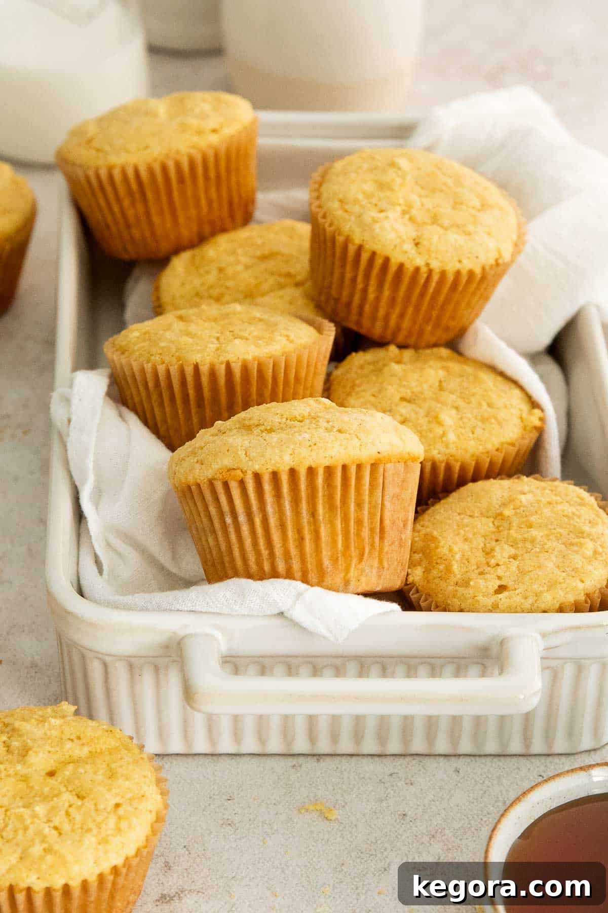 Golden-brown gluten-free corn muffins arranged in a rustic dish, accompanied by a checkered cloth.