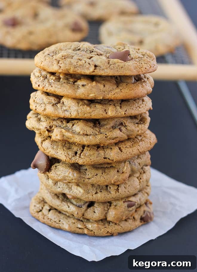 Wholesome Flourless Oatmeal Almond Butter Cookies 2 Stack of crispy-chewy flourless almond butter oatmeal cookies on white parchment paper, with a cooling rack in the background, highlighting their perfect texture.