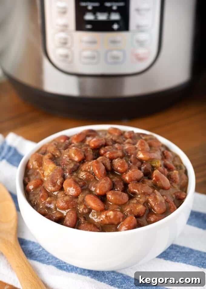 Pressure cooker Mexican Pinto Beans in white bowl in front of pressure cooker