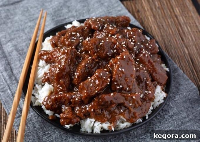 Restaurant-Style Instant Pot Mongolian Beef 3 Pressure cooker Mongolian Beef over white rice on black plate with wooden chopsticks