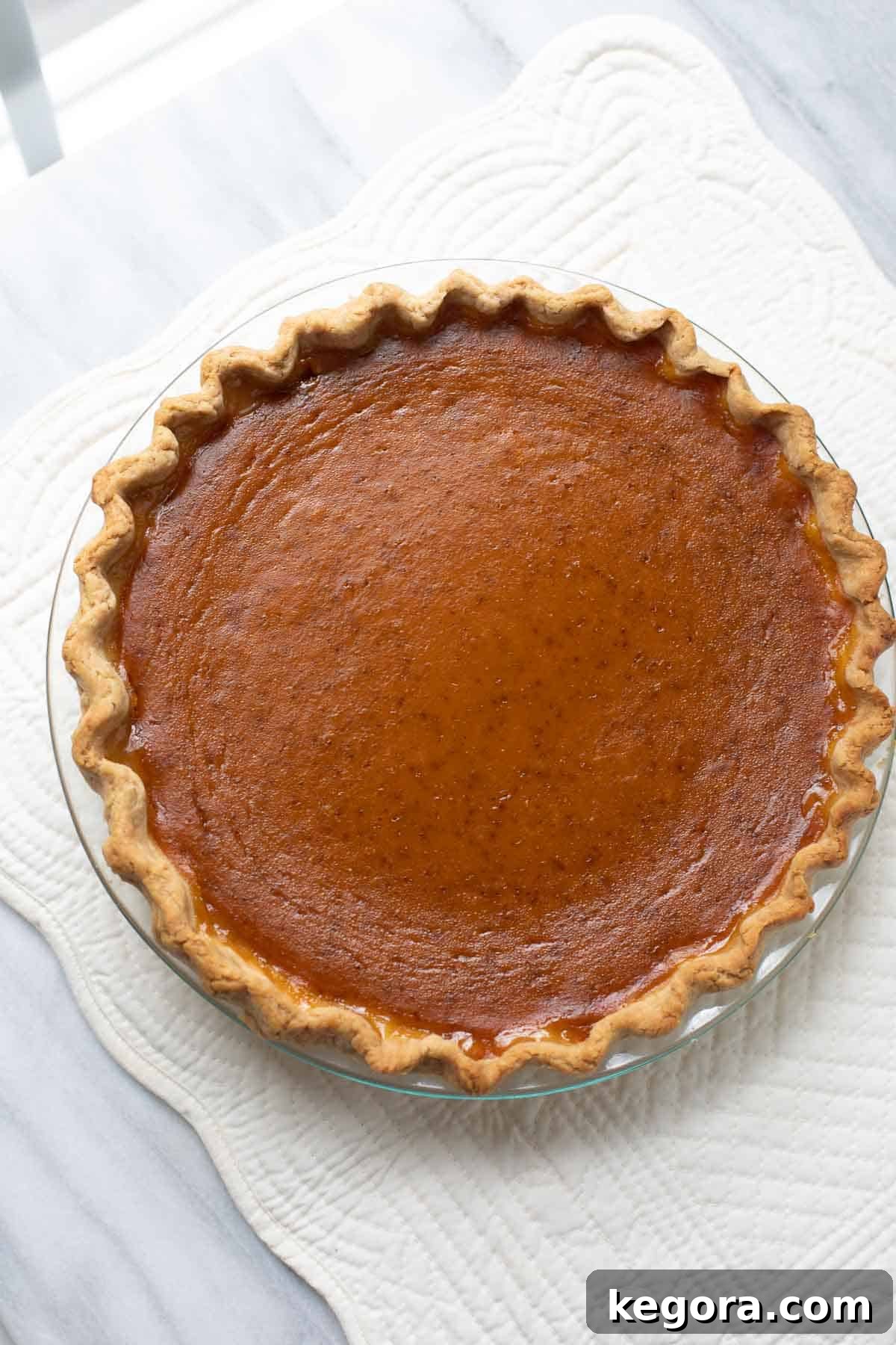 Homemade Gluten-Free Pumpkin Pie 8 Overhead shot of a baked gluten-free pumpkin pie cooling on a marble background.