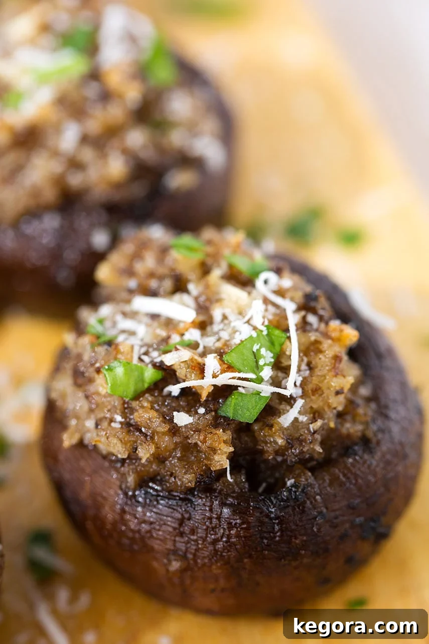 Irresistible Garlic Stuffed Mushrooms 3 A close-up view of a single Easy Garlic Stuffed Mushroom, highlighting its golden-brown topping and rich filling, presented on a wooden board.