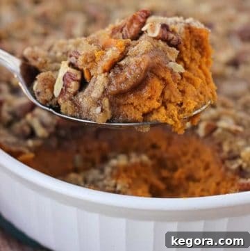 sweet potato casserole being scooped from white casserole dish with red and orange napkin