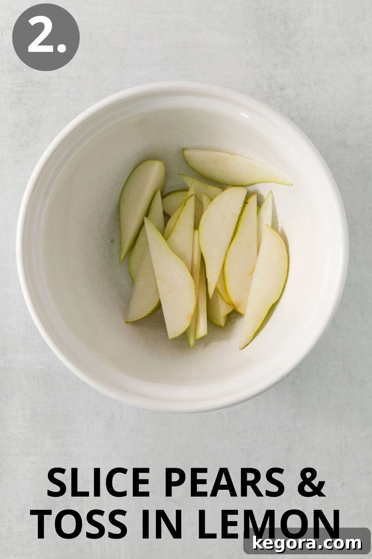 Sliced pears tossed with lemon juice in a white bowl