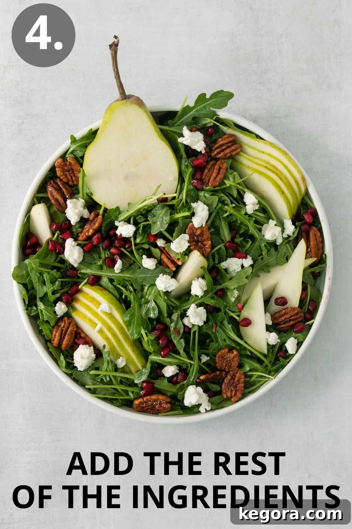 The fully assembled arugula pear salad with all ingredients in a large bowl