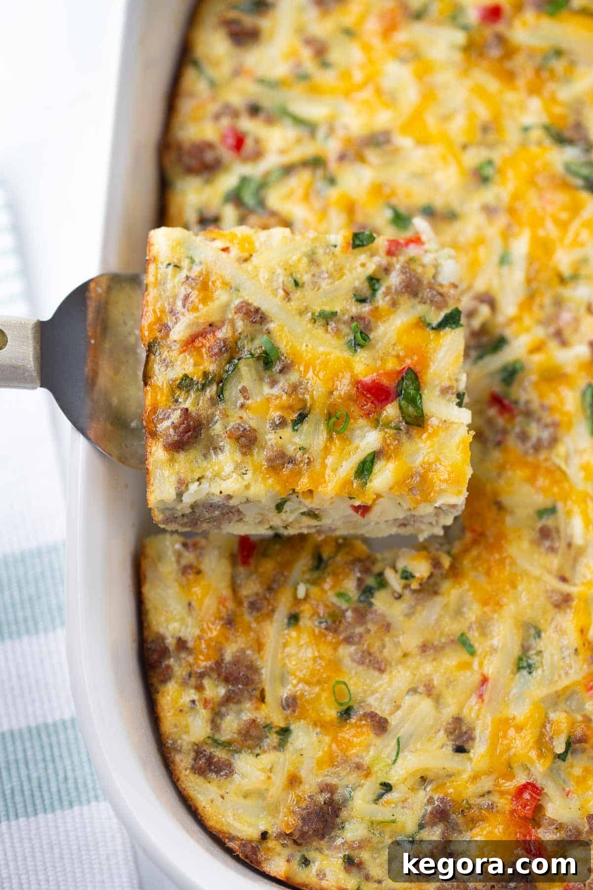 breakfast casserole being served from white casserole dish with spatula.