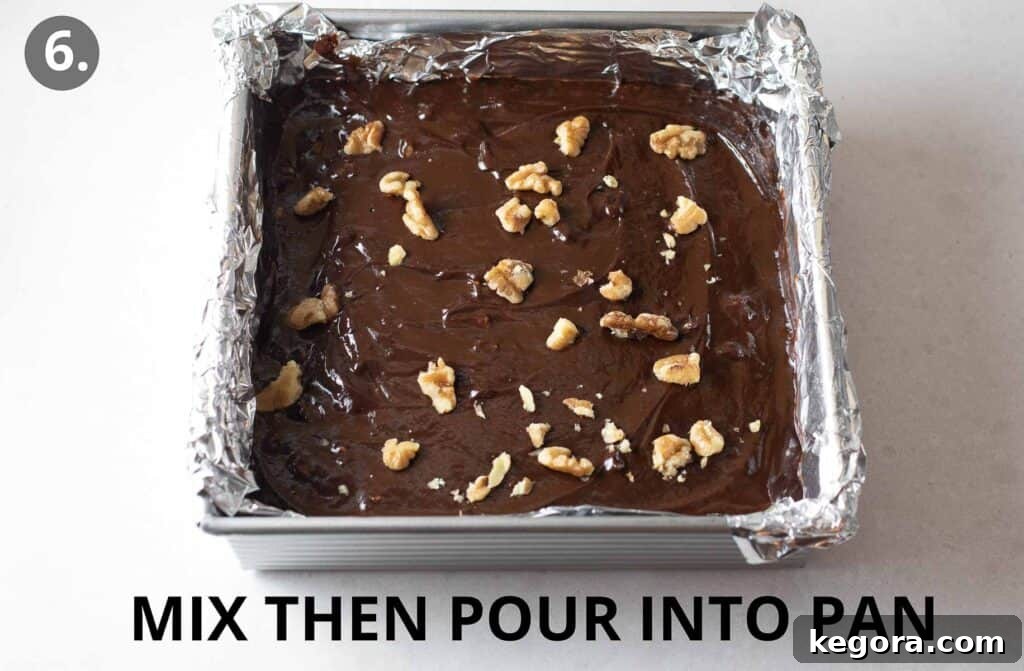 Simple Vegan Fudge 8 Smooth dairy-free fudge mixture poured into a parchment-lined pan, topped with chopped walnuts, ready to be refrigerated for setting.