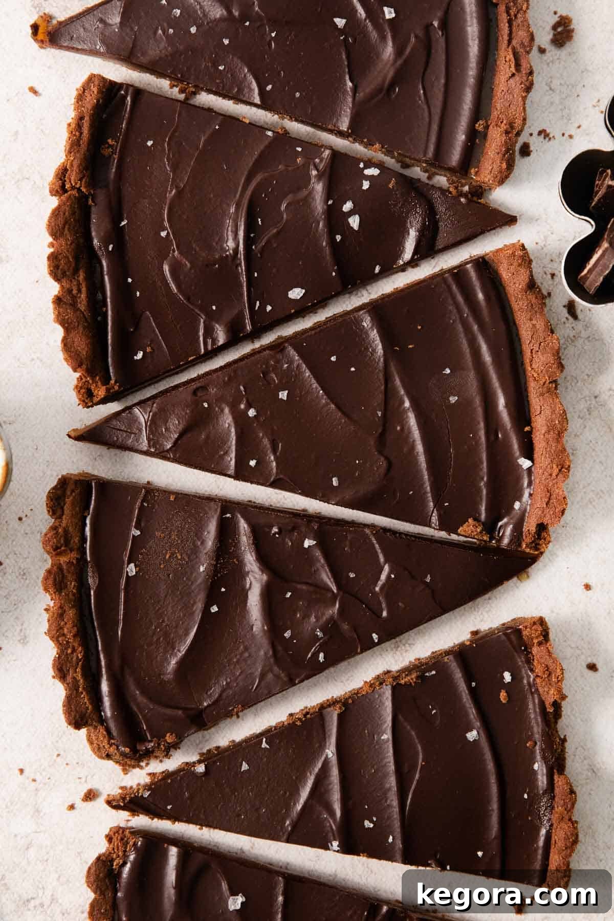 Rows of perfectly sliced gluten-free chocolate caramel tart, showcasing the distinct layers on a countertop