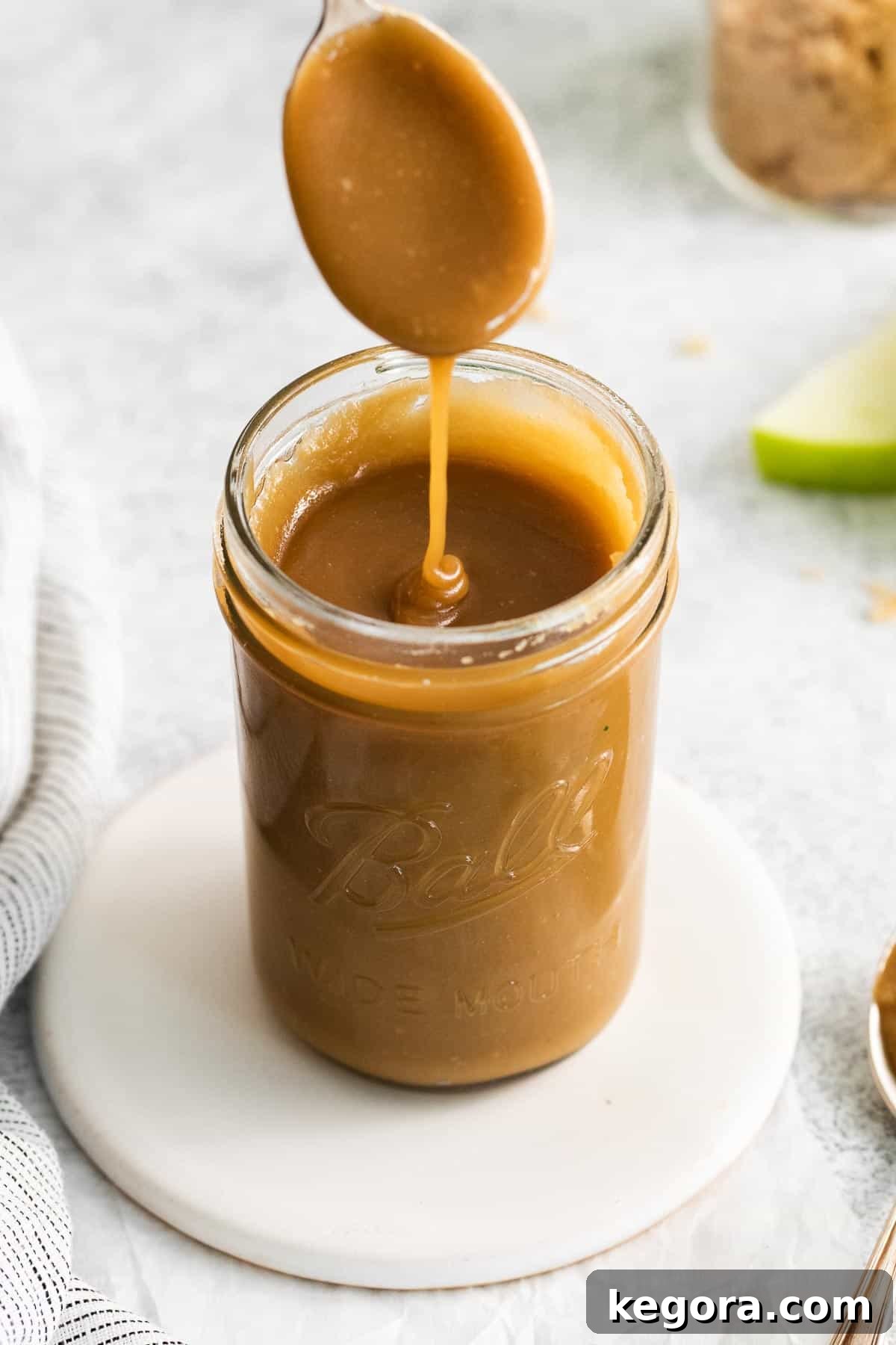A spoonful of caramel drizzling in a jar