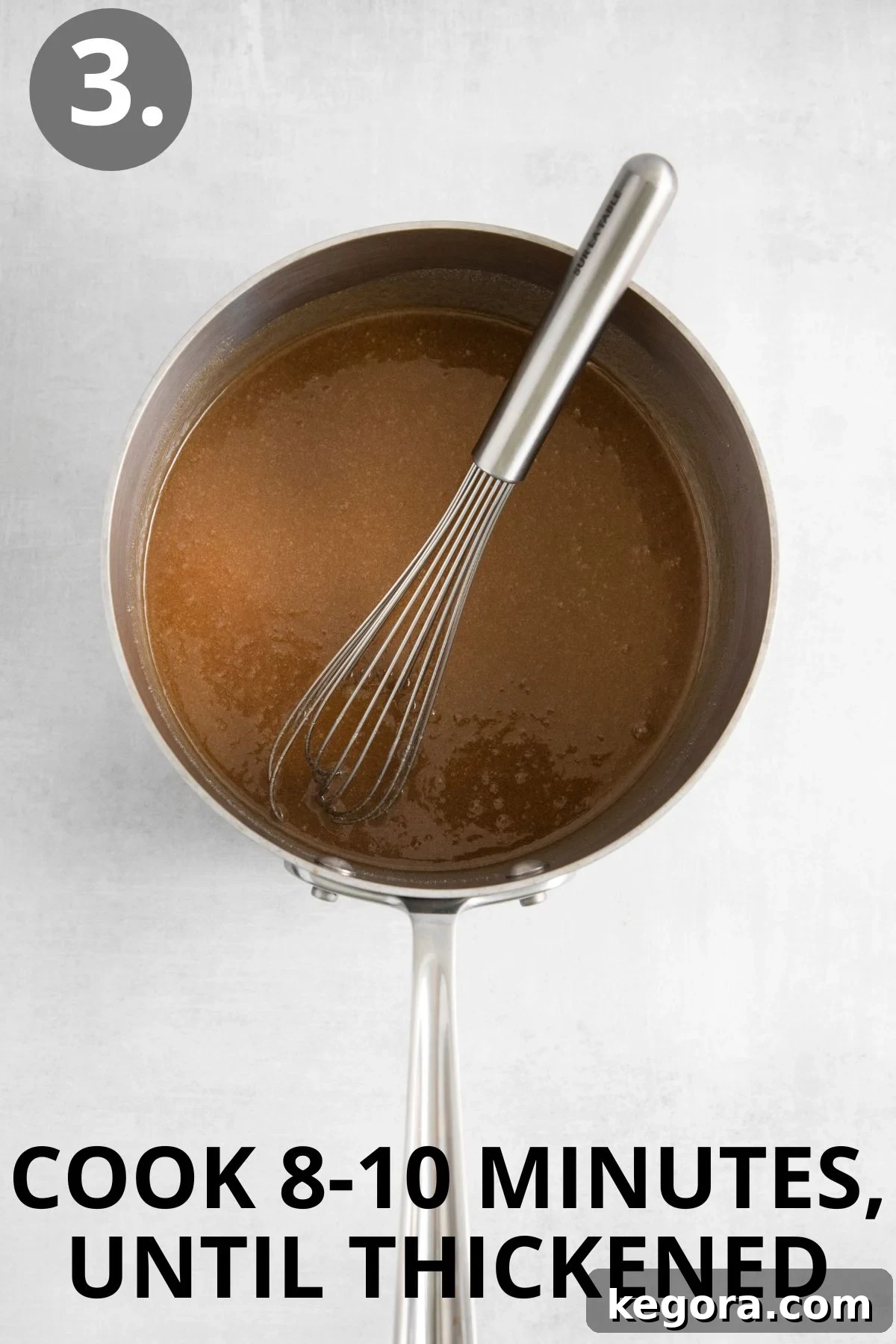 A whisk in a sauce pan of caramel sauce