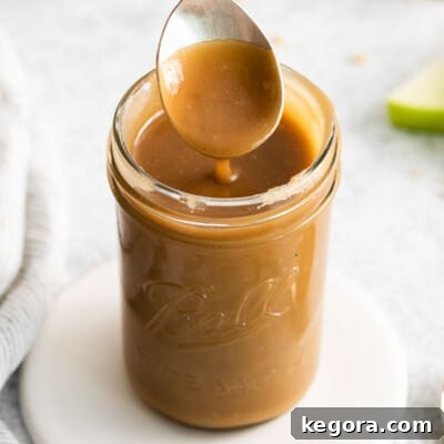 A spoonful of caramel touching a jar