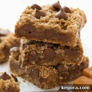 stack of gluten free oatmeal cookie bars with chocolate and caramel on white marble background