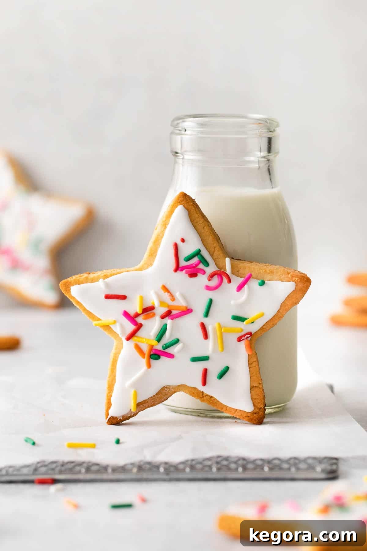 Ultimate Almond Flour Sugar Cookies 9 sugar cookie with frosting leaning against jug of milk