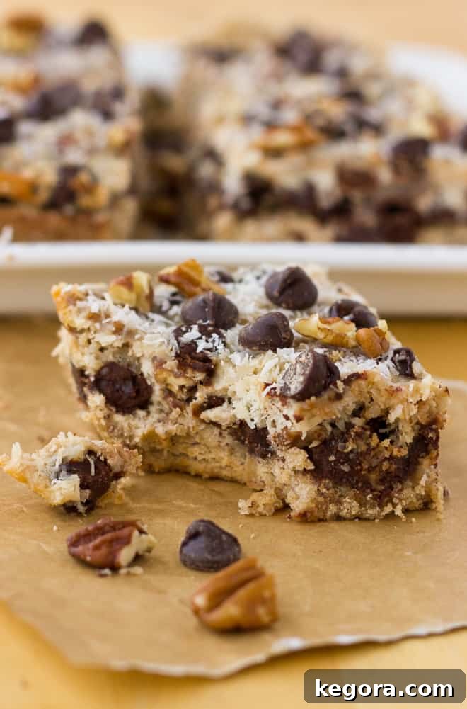 Grain-Free Magic Cookie Bar with a bite taken out, resting on parchment paper