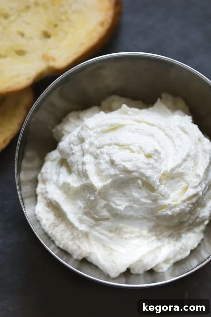 Fluffy Feta Dip 2 A small metal bowl filled with creamy whipped feta spread, with perfectly toasted bread slices blurred in the background, ready for dipping.
