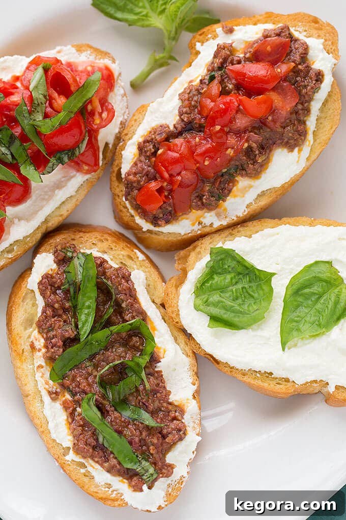Mediterranean Olive Tapenade 3 Four perfectly toasted pieces of bread, generously topped with creamy whipped feta spread and rich, homemade Olive Tapenade, arranged enticingly on a crisp white plate.
