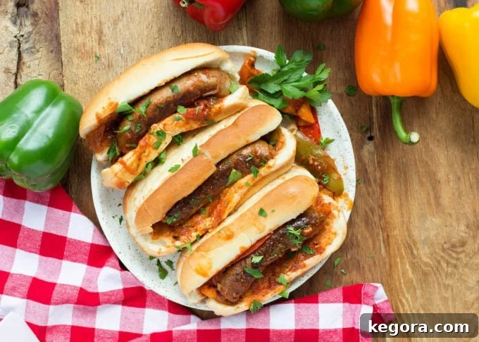 three sausage and peppers on hoagie rolls on a white plate on a wood background