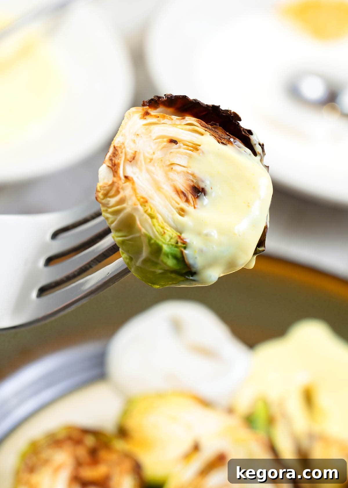 close up of a brussels sprout on a fork with aioli on it