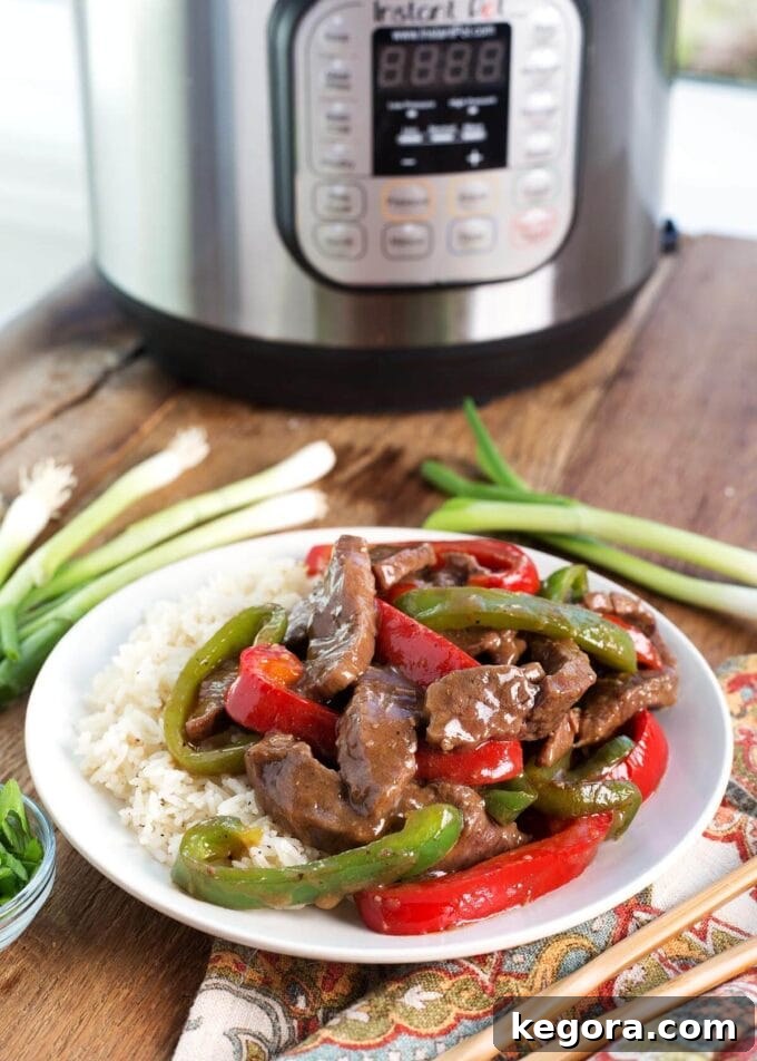 Delicious Instant Pot Pepper Steak served on a white plate with Instant Pot in the background