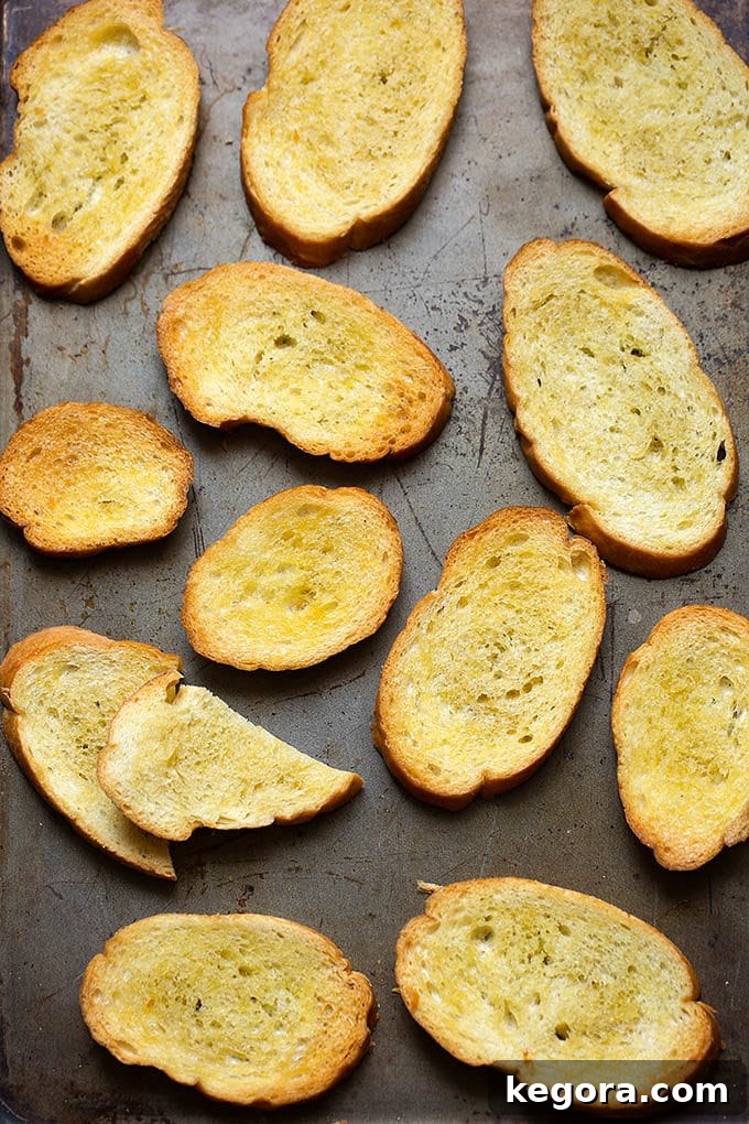 Crisp Canvas 2 Several golden brown crostini slices arranged neatly on a metal baking sheet, ready for toppings.