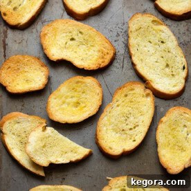 Crisp Canvas 3 Several Crostini on metal baking sheet, glistening with olive oil and golden brown.