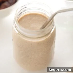 Mason jar glass with banana date smoothie and metal straw
