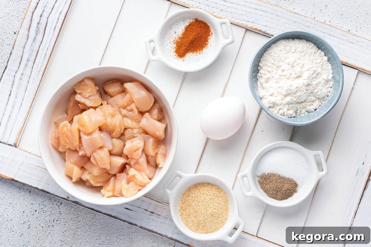 Ingredients for making Air Fryer Popcorn Chicken laid out on a wooden surface
