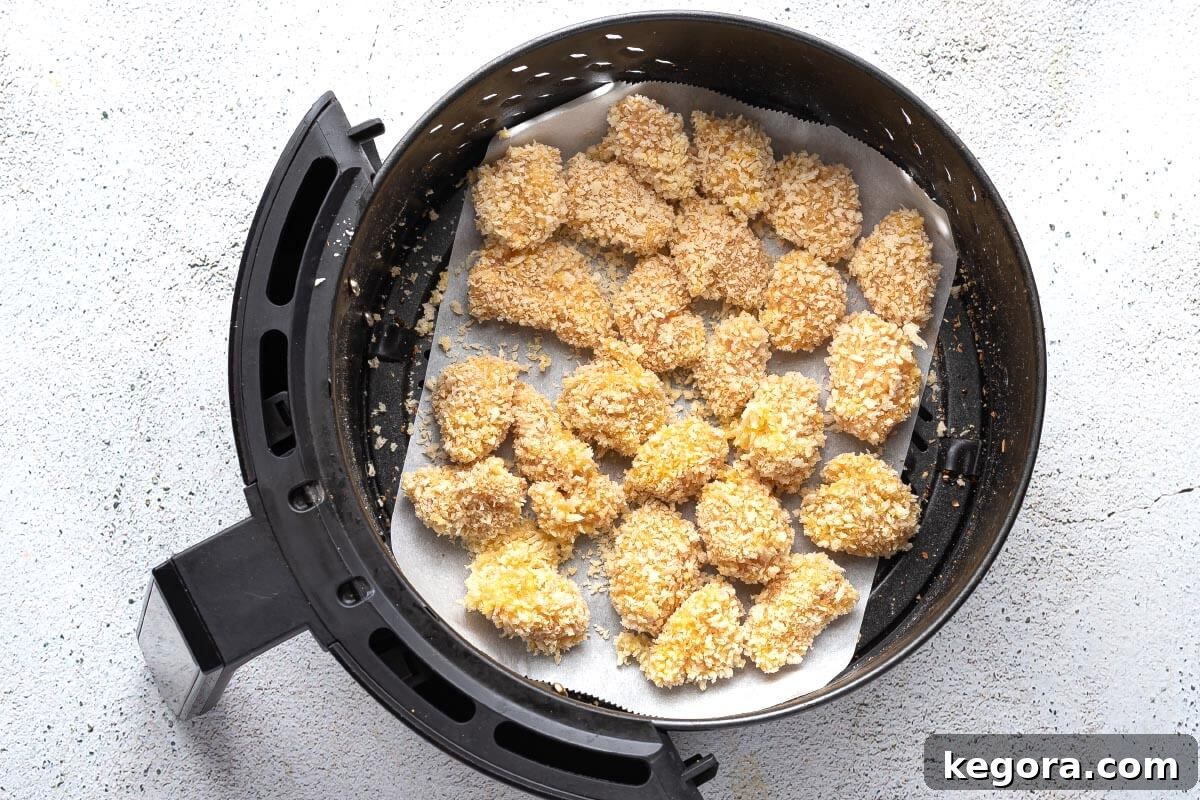 Breaded popcorn chicken pieces arranged in an air fryer basket before cooking