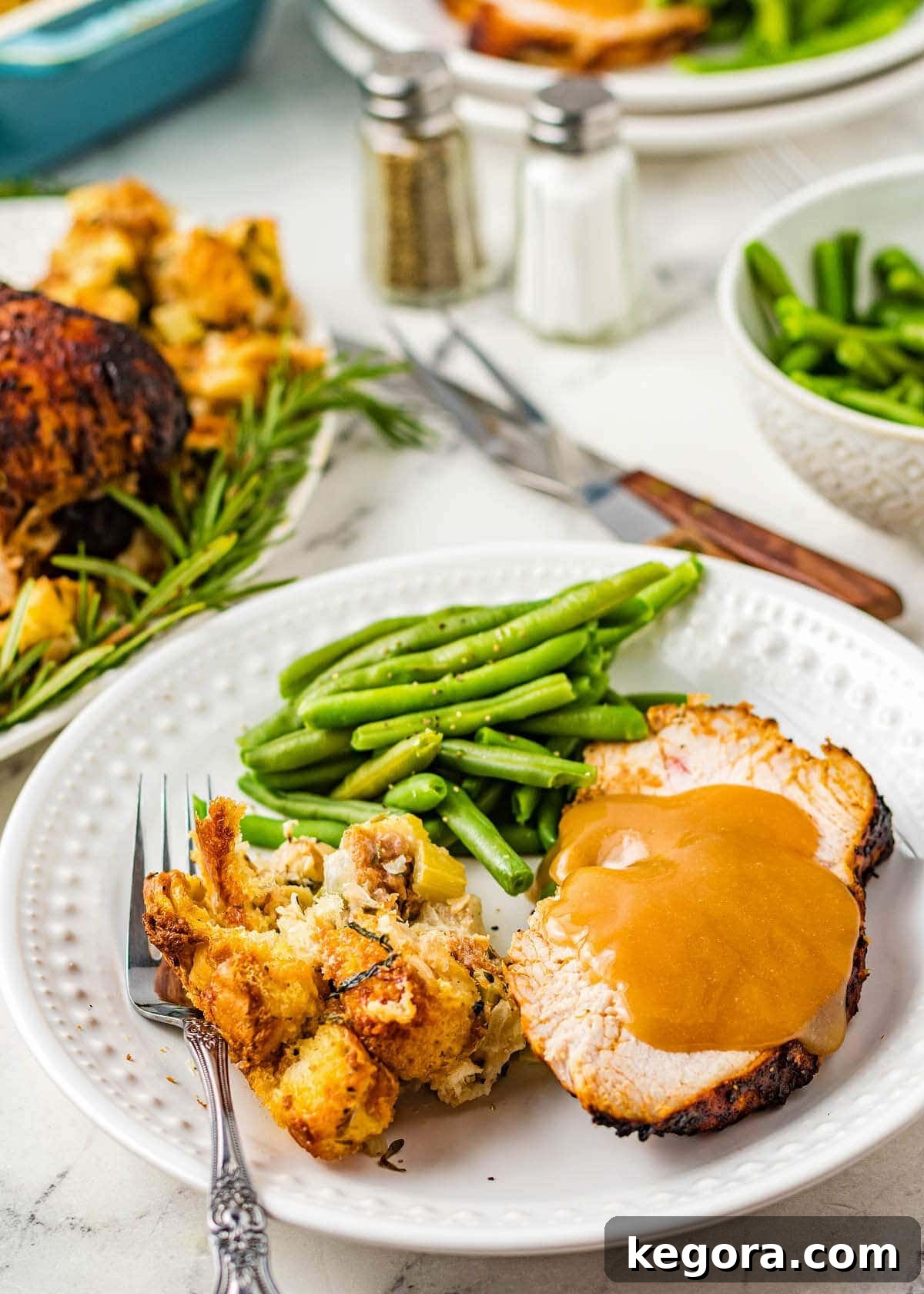 A succulent slice of Air Fryer Turkey Breast on a white plate, accompanied by green beans and savory stuffing, ready to be enjoyed.